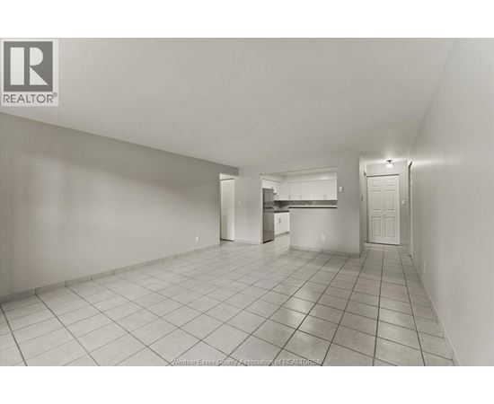 A spacious empty room with tiled flooring and white walls.