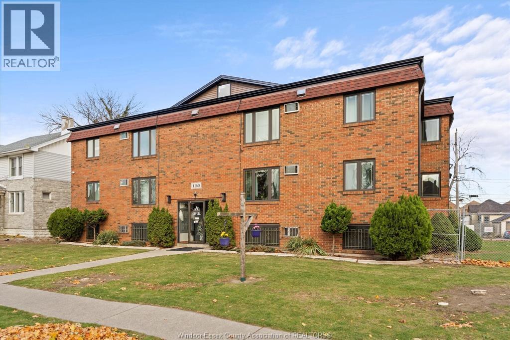 A red brick building with a black fence in front.