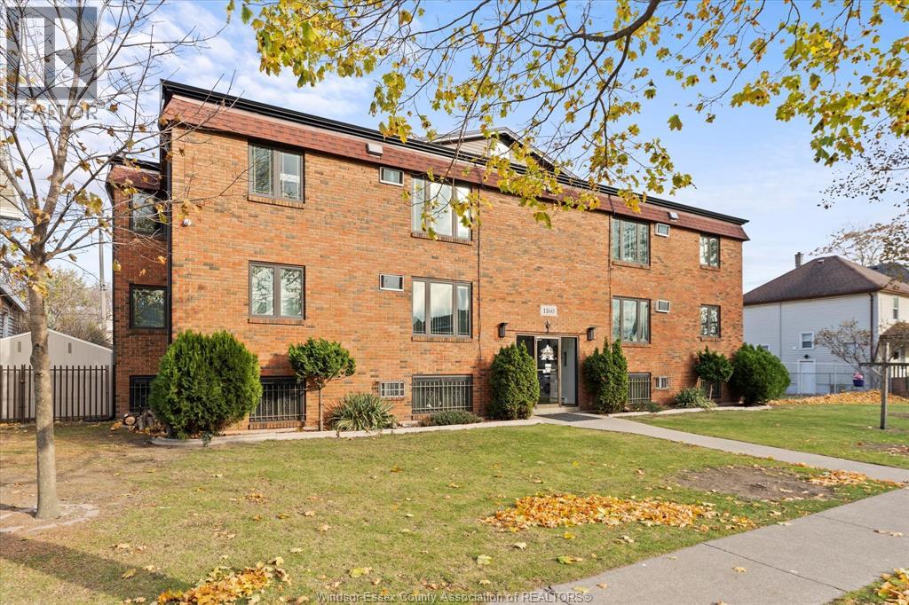 A red brick building with a black fence and a tree with yellow leaves in front.