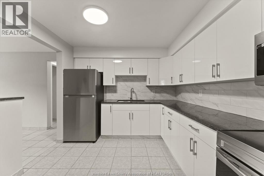 A kitchen with white cabinets and a black counter top.
