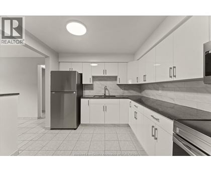 A kitchen with white cabinets and a black counter top.