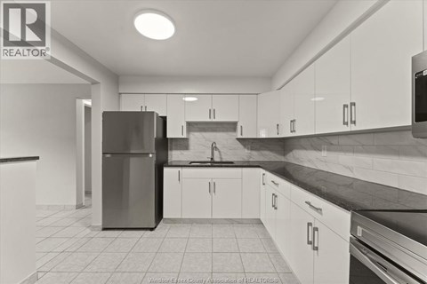 A kitchen with white cabinets and a black counter top.