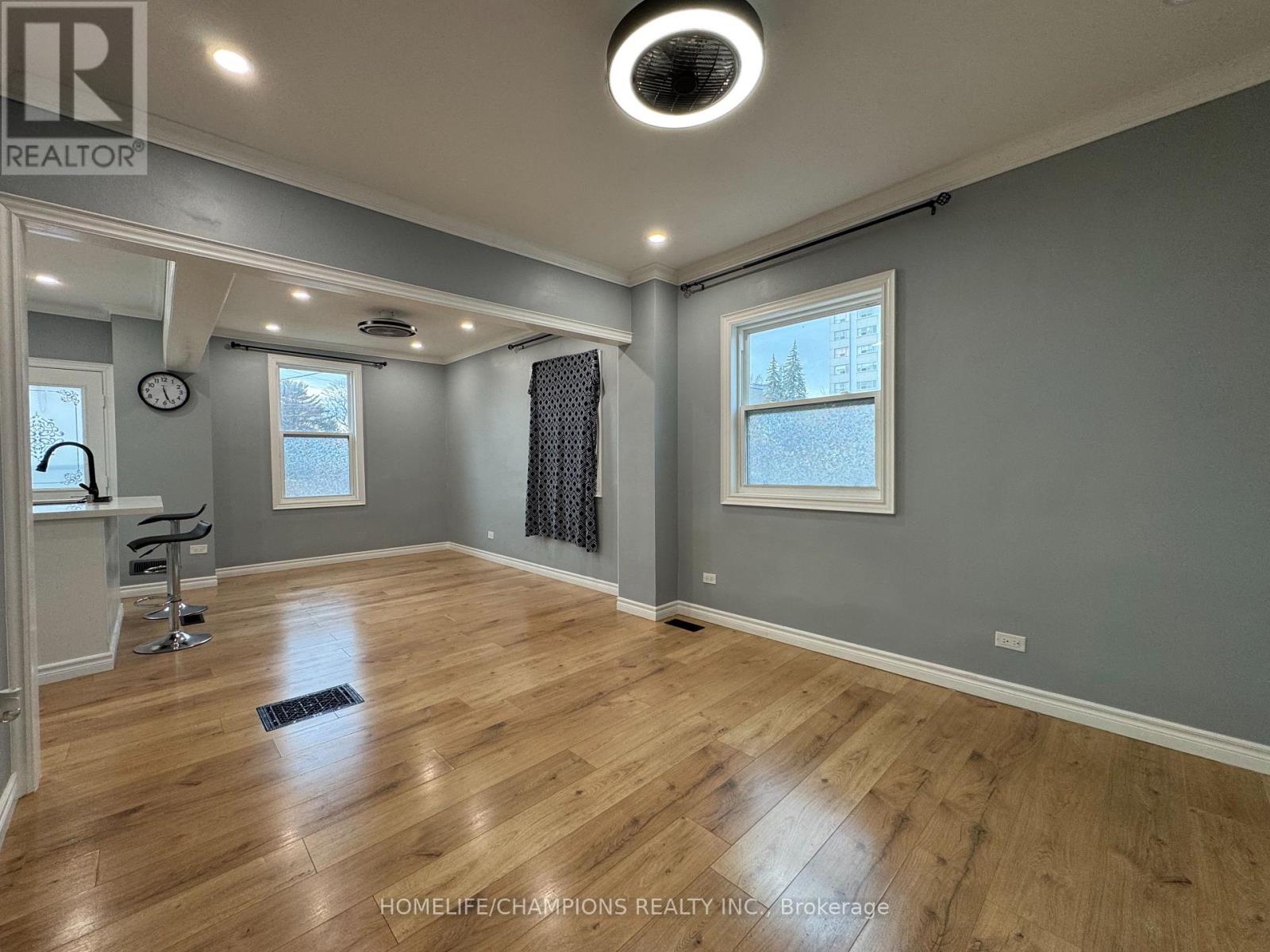 A spacious room with wooden flooring and a ceiling light fixture.