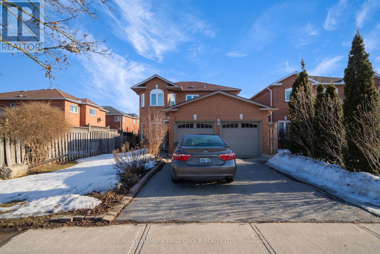 A car is parked in front of a house with a garage.