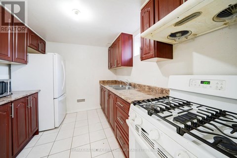 A kitchen with a white gas stove and brown cabinets.
