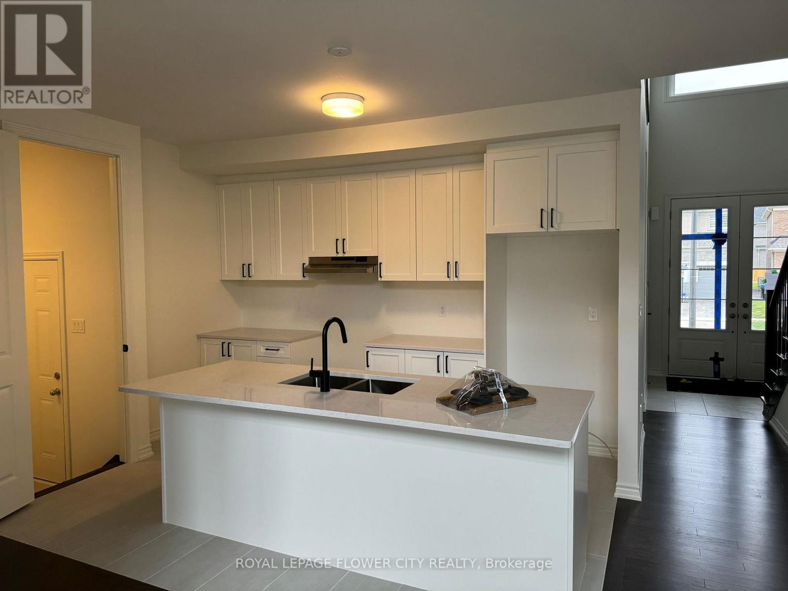 A kitchen with white cabinets and a white island with a sink.