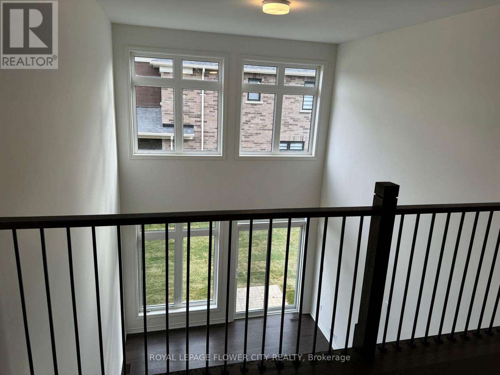 A balcony with a black railing and a window showing a view of a building.