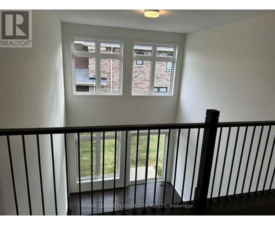 A balcony with a black railing and a window showing a view of a building.