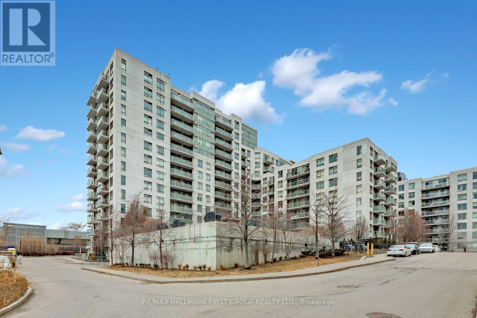 A large, modern apartment building with a parking lot in front.