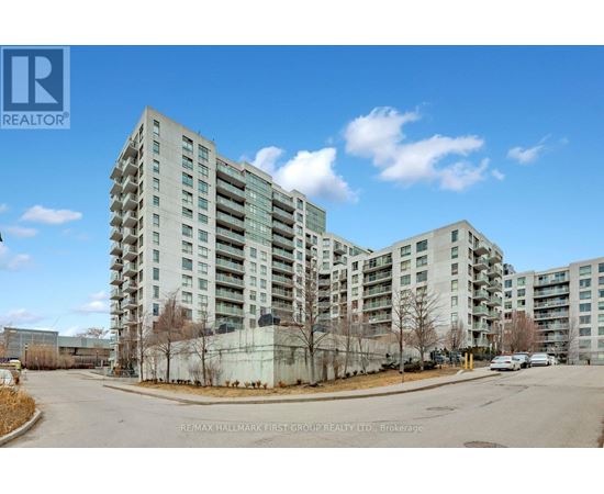 A large, modern apartment building with a parking lot in front.