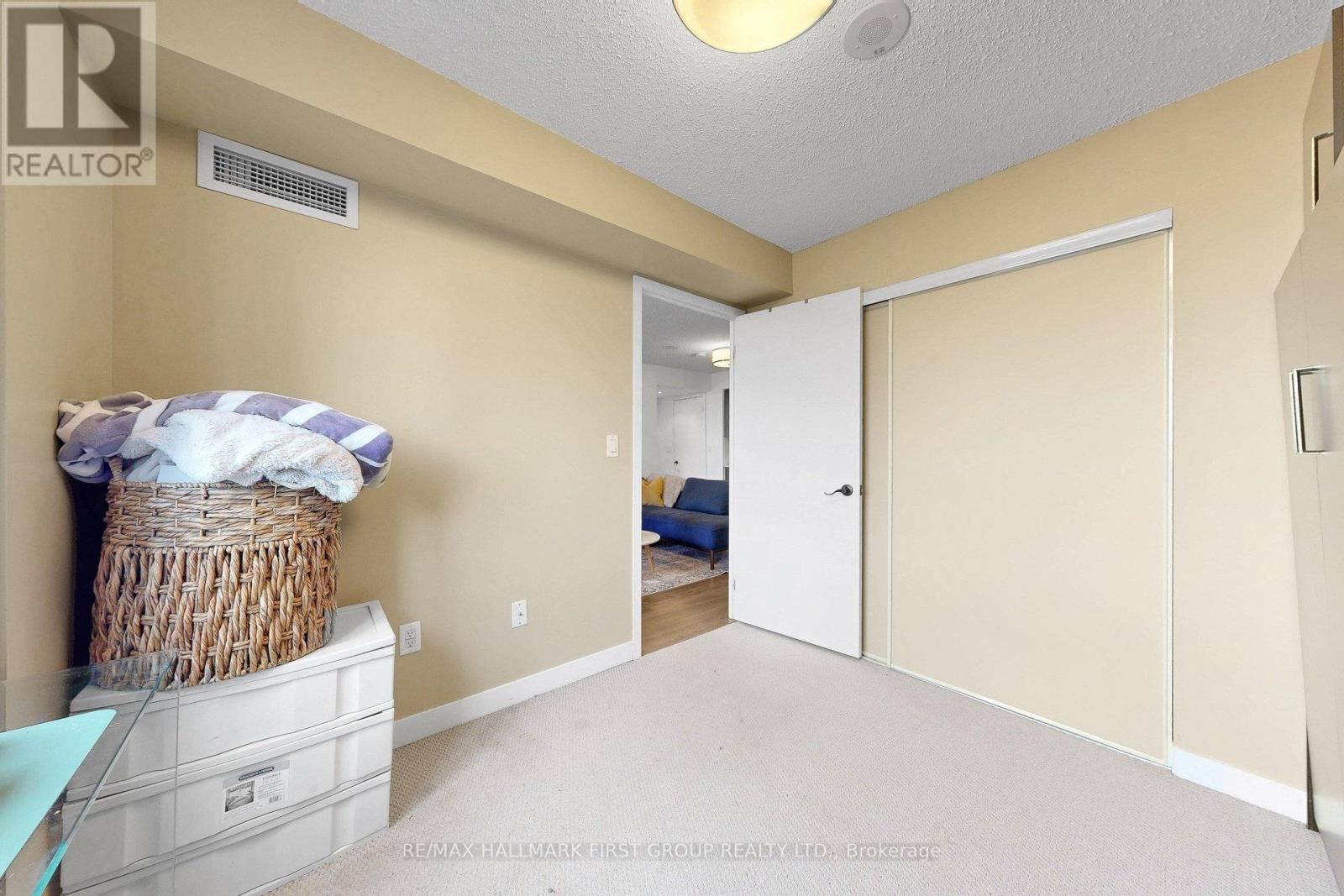 A bedroom with a bed and a wicker basket on a dresser.