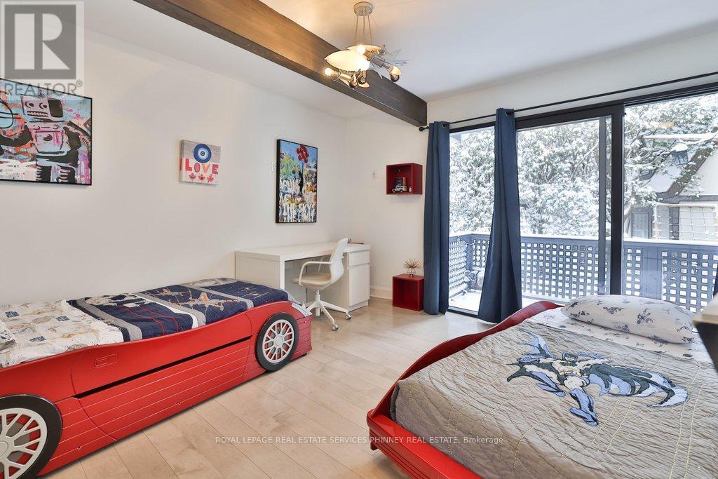 A bedroom with a red car-themed bed and a white desk with a chair.