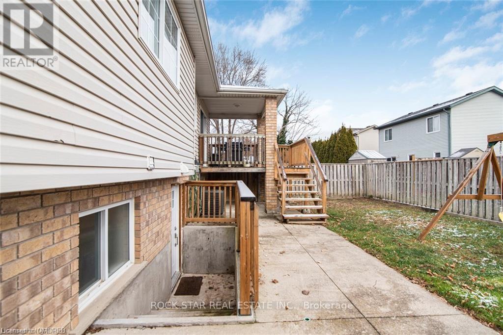 A house with a wooden deck and stairs leading to a basement entrance.