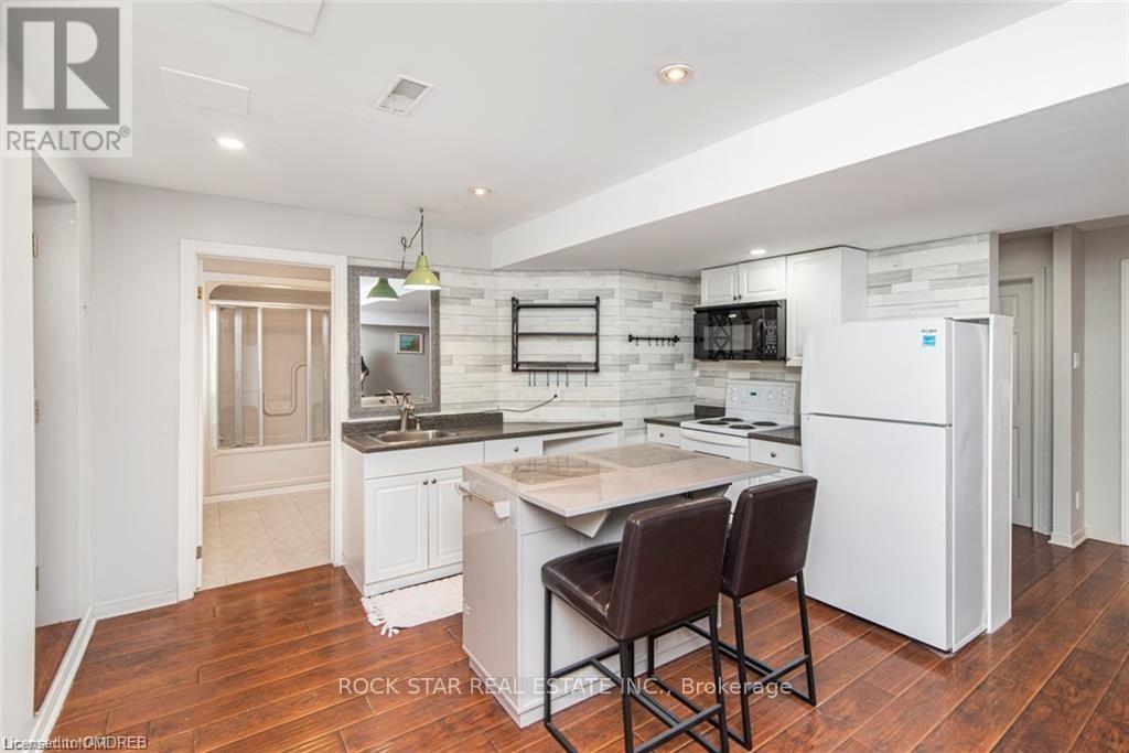A modern kitchen with white appliances and a wooden floor.
