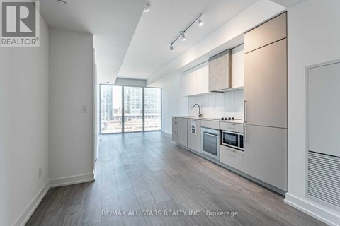A spacious kitchen with white cabinets and a large window.