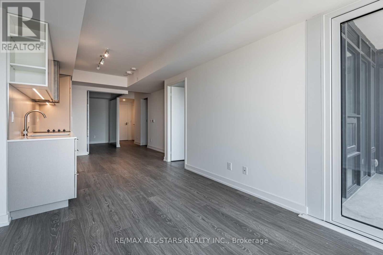 A spacious room with a grey floor and white walls, with a large window on the right side.