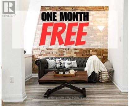 A living room with a black couch and a brick wall with the words "ONE MONTH FREE" written on it.