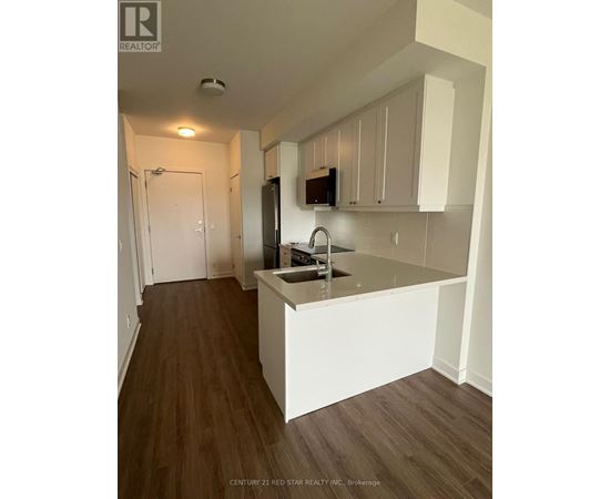 A kitchen with white cabinets and a wooden floor.