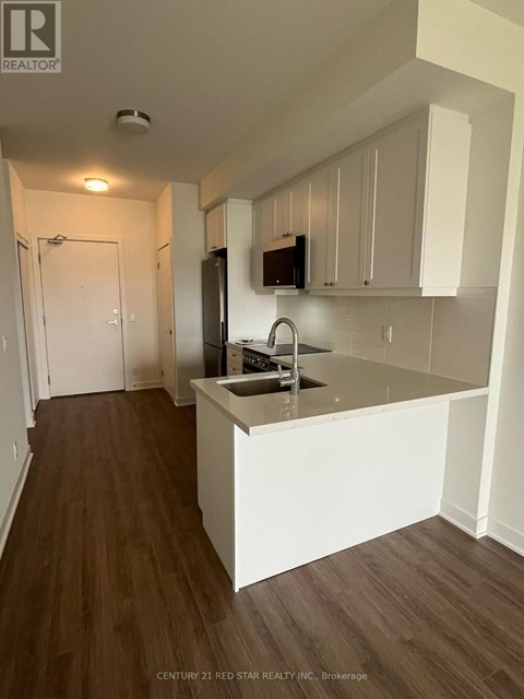 A kitchen with white cabinets and a wooden floor.