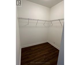 A room with white walls and wooden flooring with clothes hangers on the rail.
