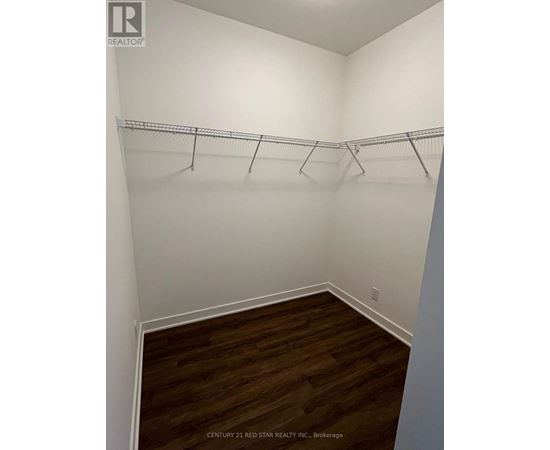A room with white walls and wooden flooring with clothes hangers on the rail.