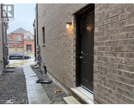 A brick building with a black door and a gravel pathway leading to it.