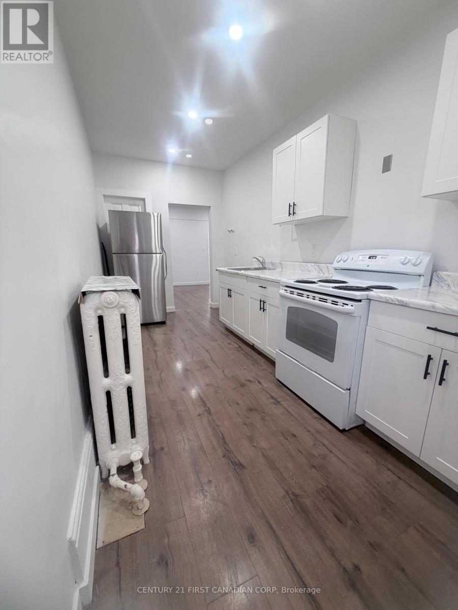 A white kitchen with wood floors and a white stove top oven.