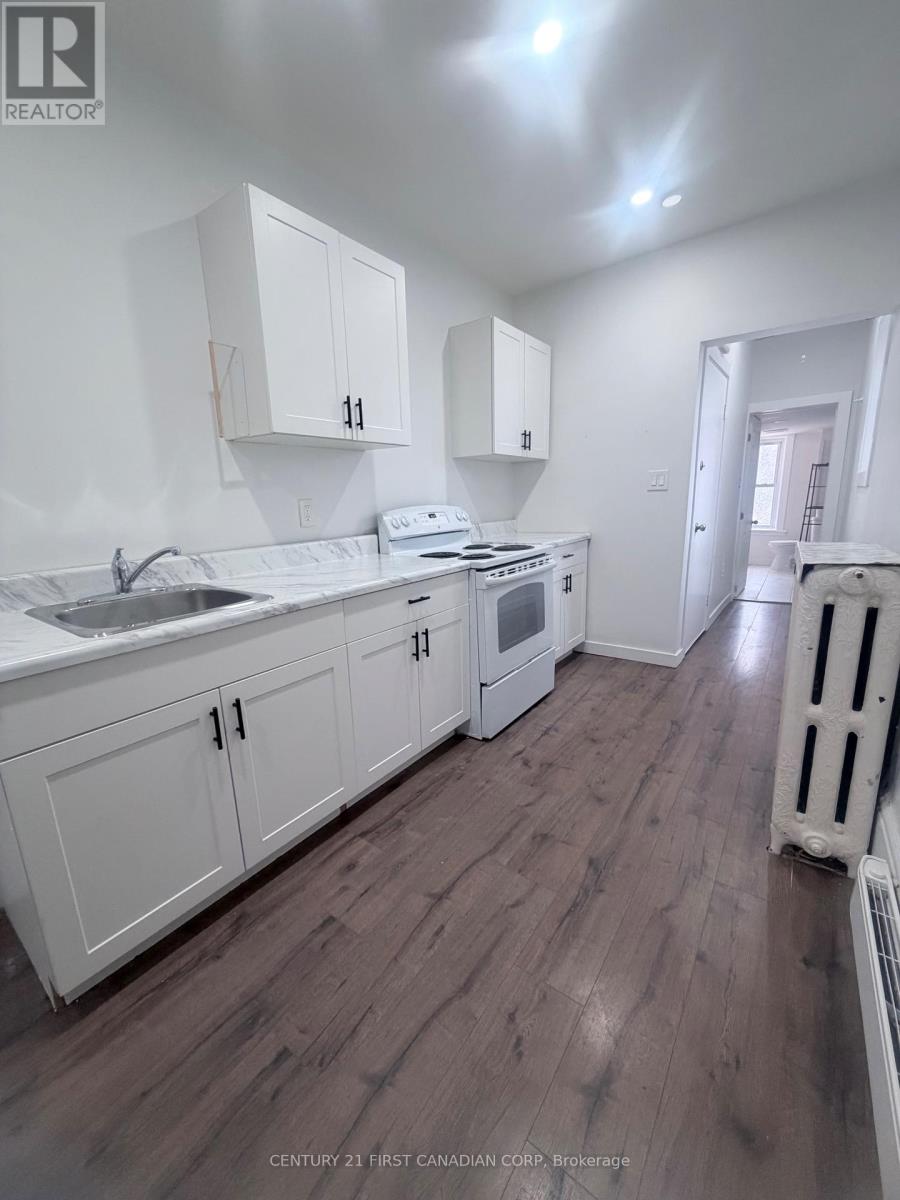 A kitchen with white cabinets and a wooden floor.