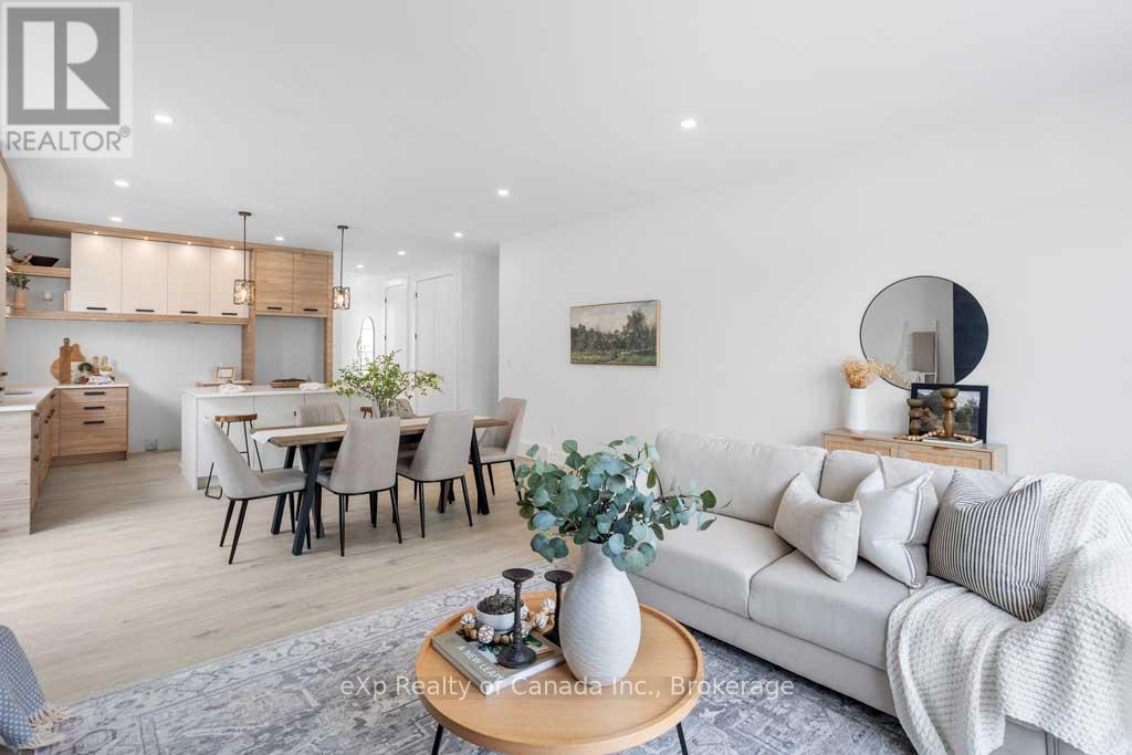 A modern living room with a white sofa, a wooden coffee table, and a dining area in the background.