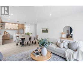 A modern living room with a white sofa, a wooden coffee table, and a dining area in the background.