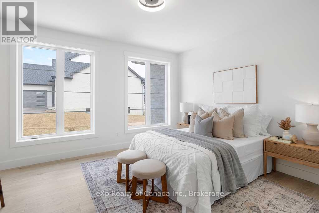 A bedroom with a bed, a bench, and a window overlooking a yard.