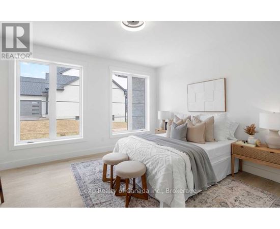 A bedroom with a bed, a bench, and a window overlooking a yard.