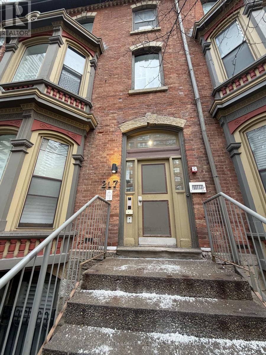 A brown door is on the front of a red brick building.