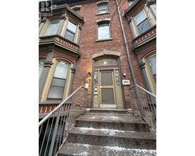 A brown door is on the front of a red brick building.