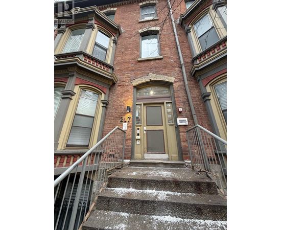 A brown door is on the front of a red brick building.