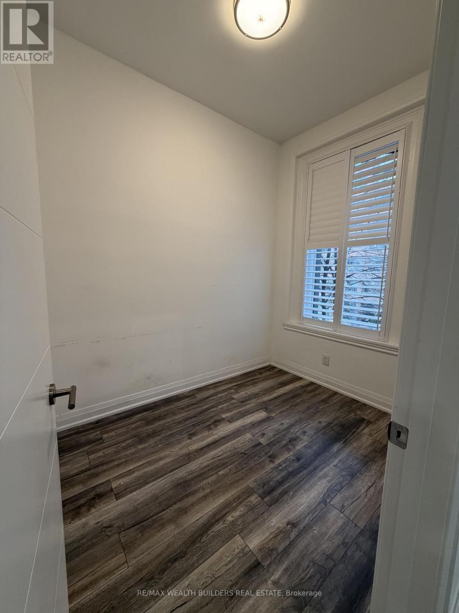 A room with wooden flooring and a window with blinds.