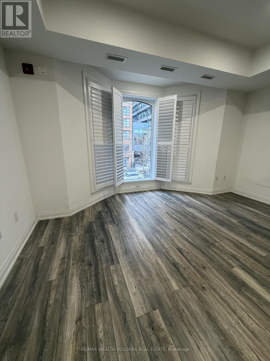 A room with wooden flooring and a window with blinds.