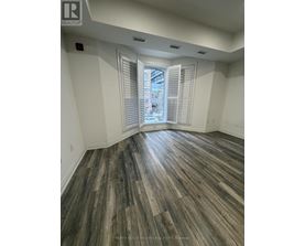 A room with wooden flooring and a window with blinds.