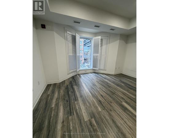 A room with wooden flooring and a window with blinds.
