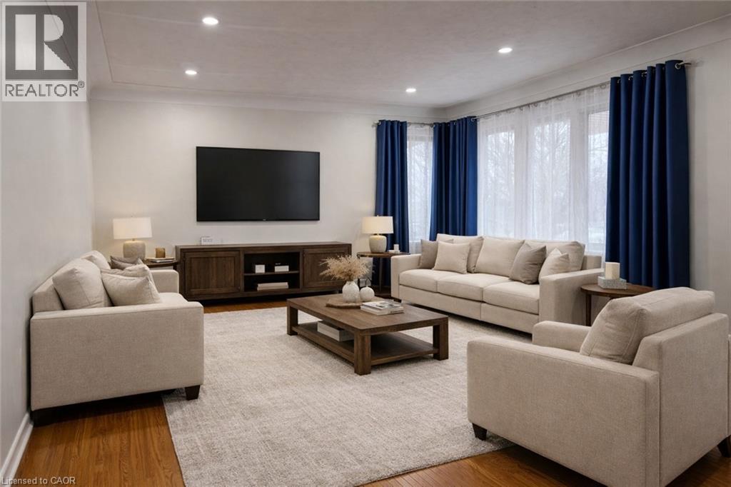 A living room with a large couch, a coffee table, and a flat screen TV mounted on the wall.