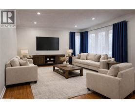 A living room with a large couch, a coffee table, and a flat screen TV mounted on the wall.