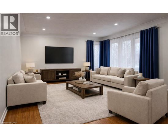 A living room with a large couch, a coffee table, and a flat screen TV mounted on the wall.