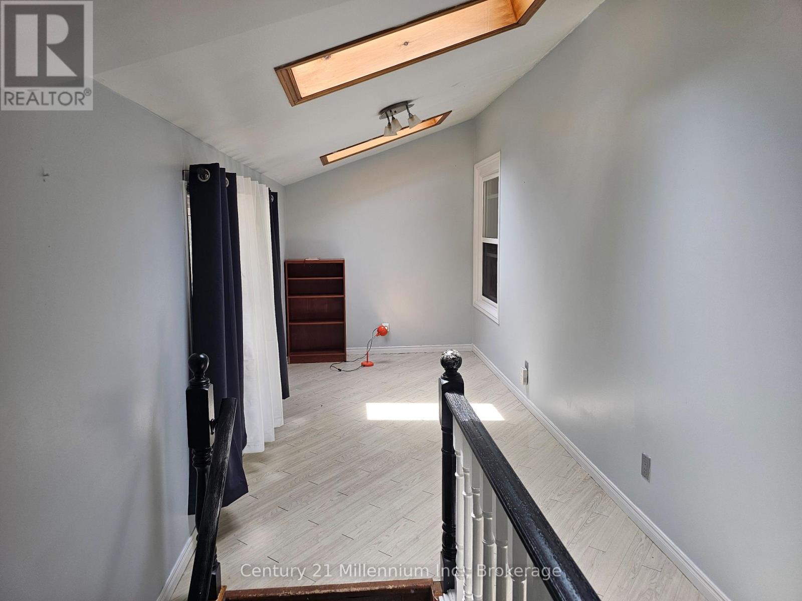 A spacious room with a wooden floor and a skylight.