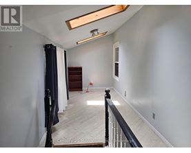 A spacious room with a wooden floor and a skylight.