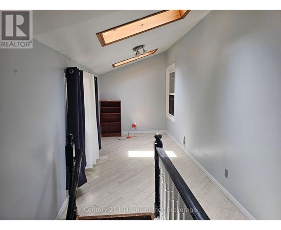A spacious room with a wooden floor and a skylight.