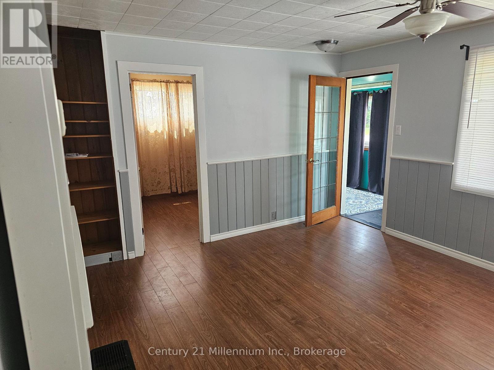 A room with wood flooring and a ceiling fan.