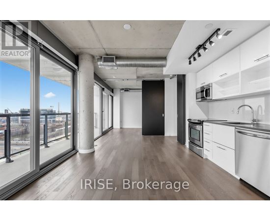 A modern kitchen with white cabinets and a black refrigerator.