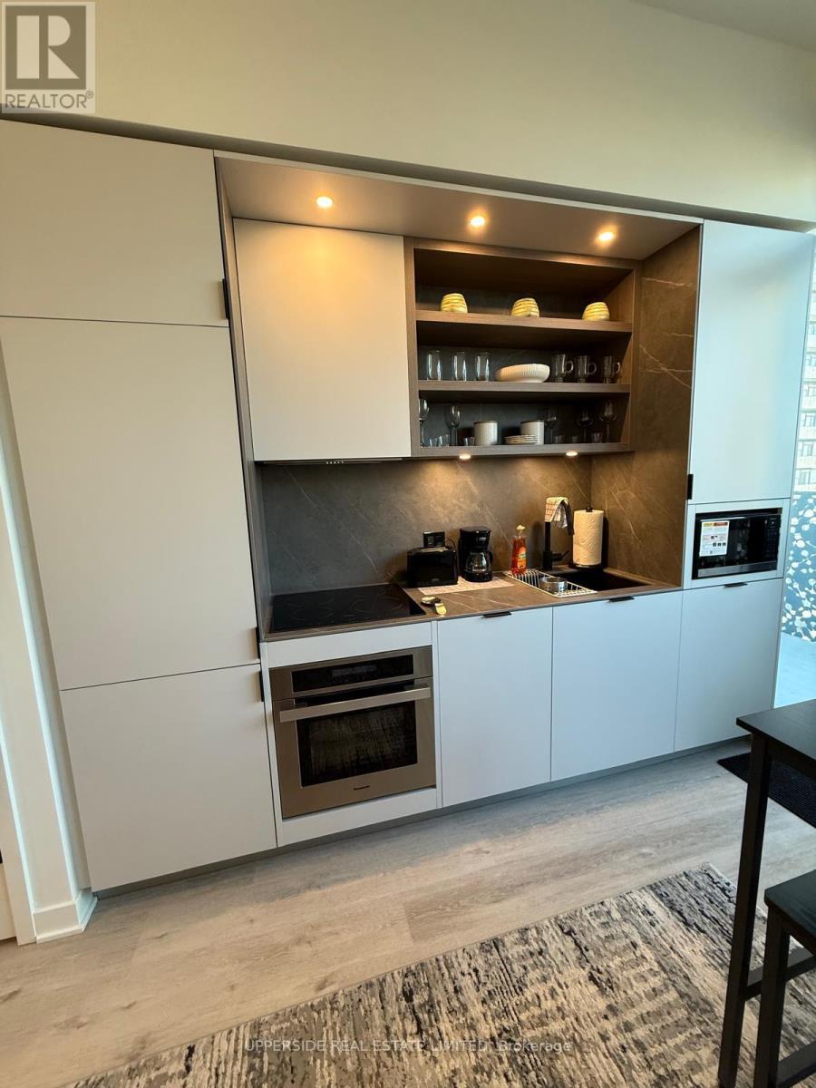 A modern kitchen with a refrigerator, oven, and microwave.