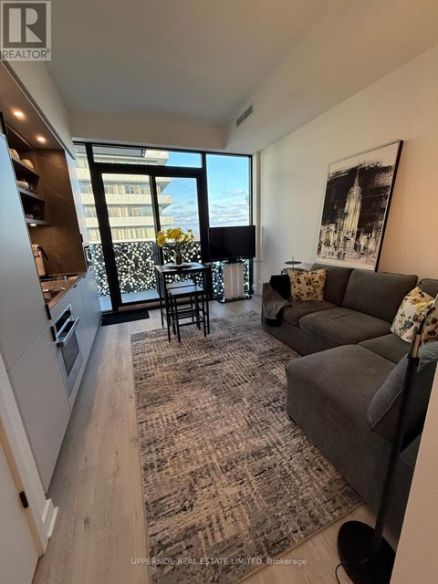 A living room with a grey couch and a rug.