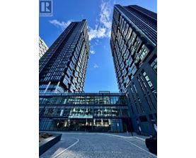 Two tall buildings with glass windows and a car parked in front of them.